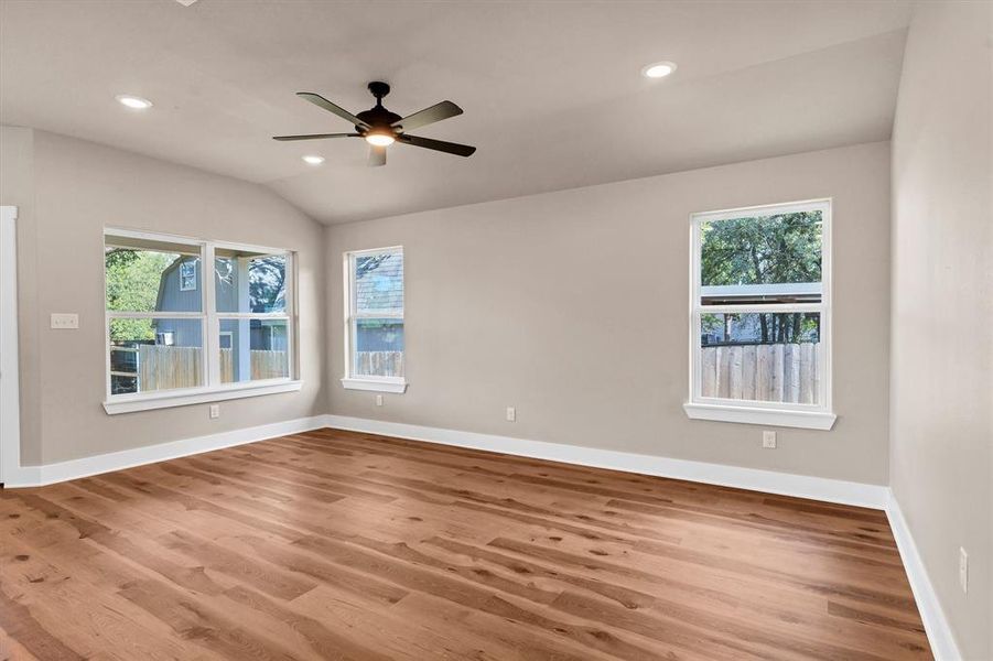 Empty room with wood finished floors, recessed lighting, lofted ceiling, and a ceiling fan Empty room with wood finished floors, recessed lighting, lofted ceiling, and a ceiling fan