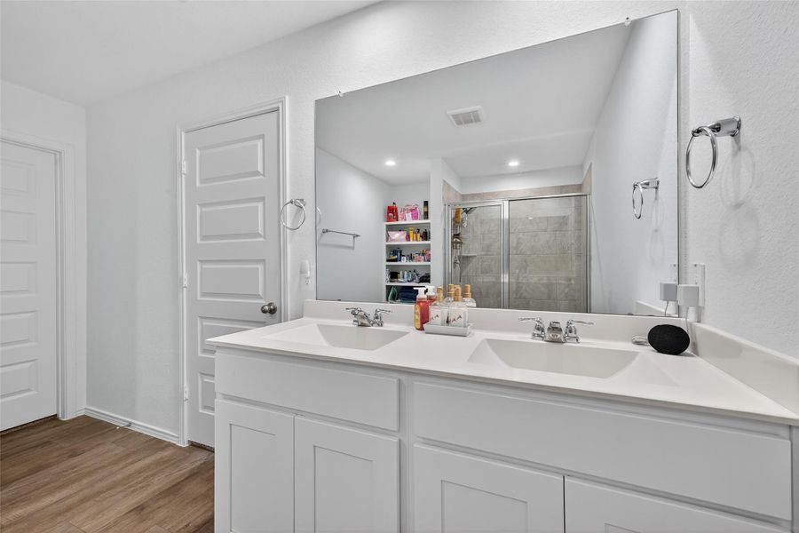 Dual vanities, exquisite finishes, and a walk-in shower create a luxurious atmosphere.