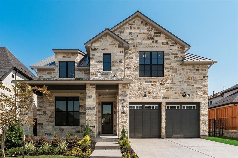 View of front of property with stone siding, an attached garage, and driveway