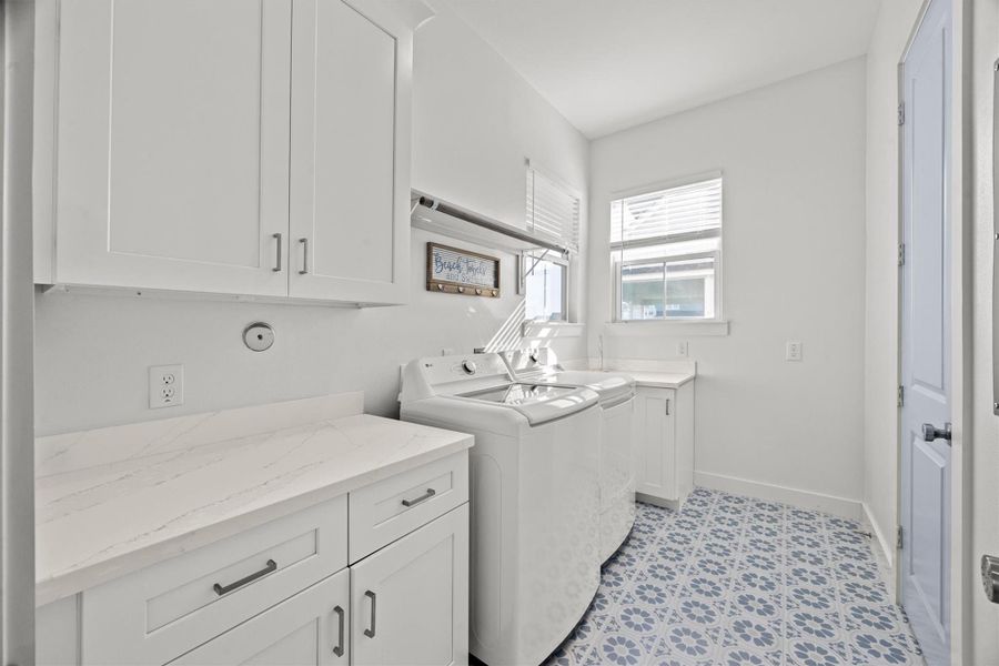 The first-floor utility room boasts fun, patterned tile, a quartz folding area, plenty of storage, a huge walk-in closet, and space for an additional refrigerator.
