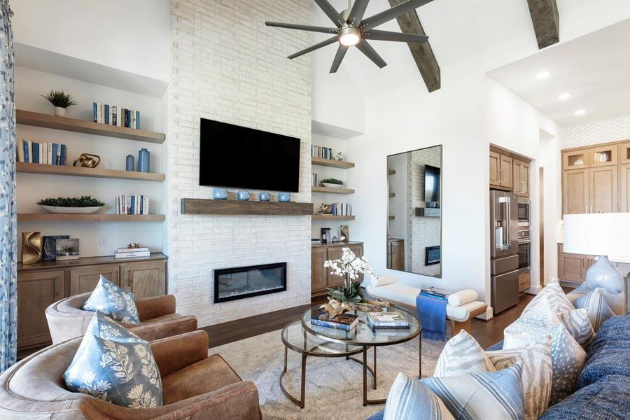 Living area with ceiling fan, wood finished floors, a large fireplace, and built in shelves Living area with ceiling fan, wood finished floors, a large fireplace, and built in shelves