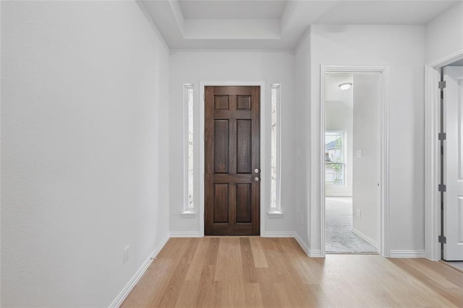 Entryway featuring light wood-type flooring and a raised ceiling