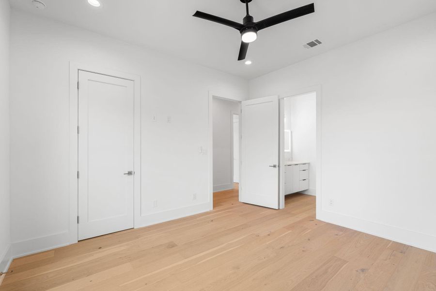 Minimalist design and ample lighting define this spacious bedroom with hardwood flooring.