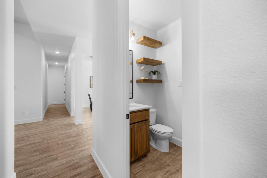 Half bath with light wood-style flooring, vanity, recessed lighting, and a textured wall