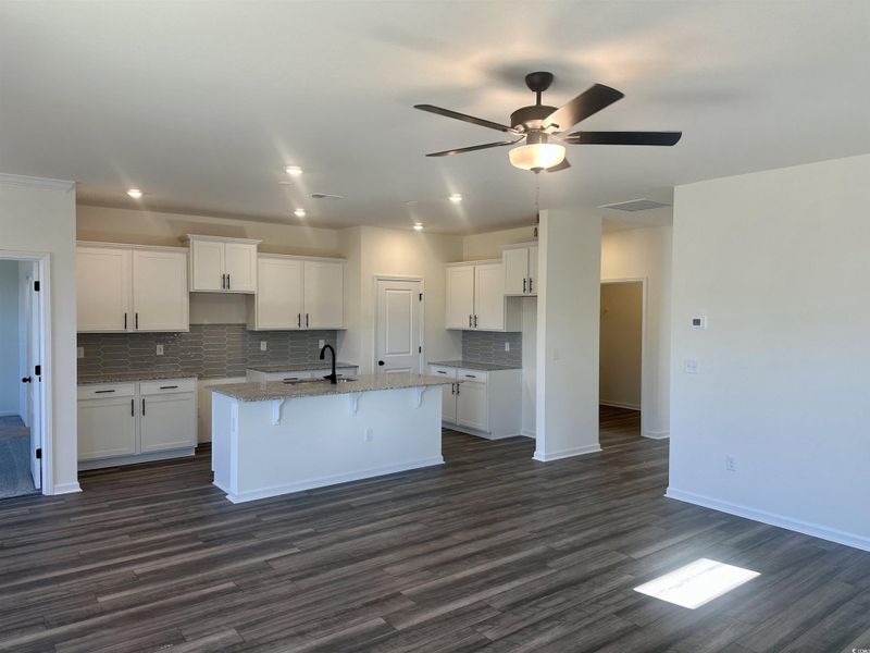 Kitchen with beautiful backsplash, a kitchen breakfast bar, granite countertops, white cabinets, and a kitchen island with sink Kitchen with beautiful backsplash, a kitchen breakfast bar, granite countertops, white cabinets, and a kitchen island with sink