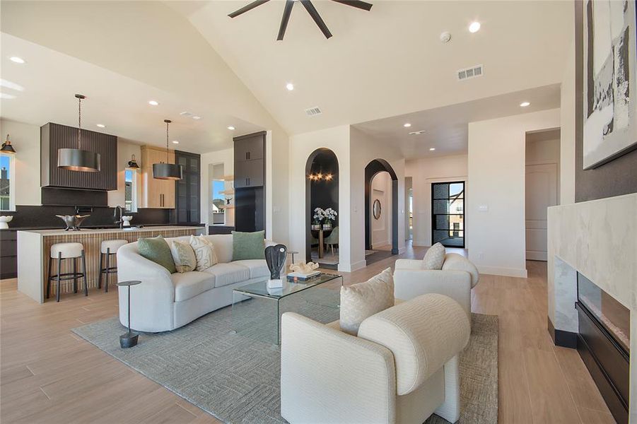 Living room featuring recessed lighting, light wood finished floors, a glass covered fireplace, arched walkways, and high vaulted ceiling Living room featuring recessed lighting, light wood finished floors, a glass covered fireplace, arched walkways, and high vaulted ceiling