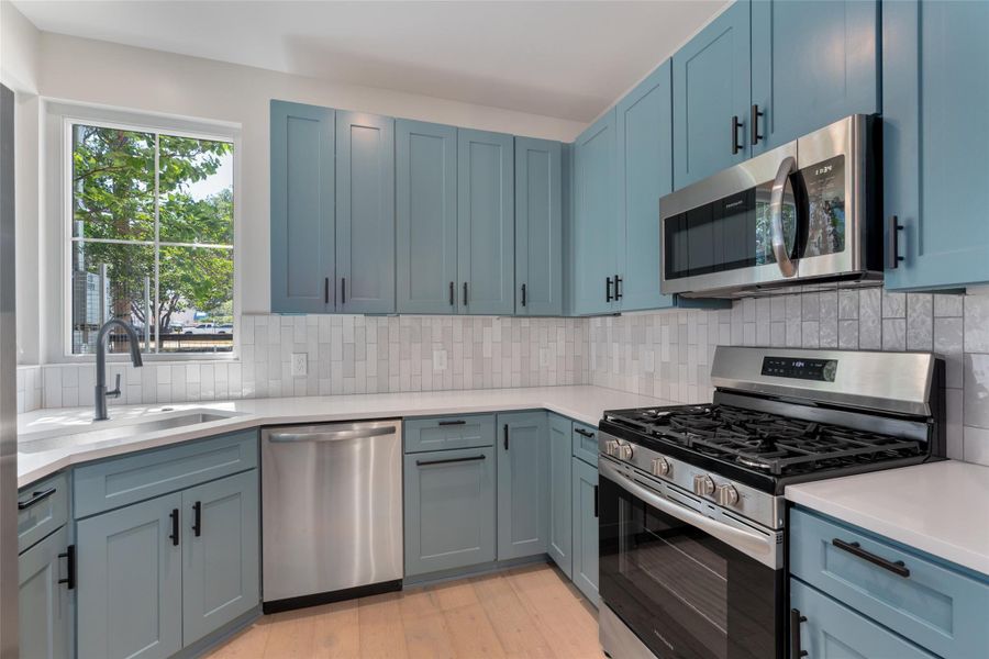 Kitchen featuring light blue cabinetry, stainless steel appliances, white quartz countertops, and a subway tile backsplash Kitchen featuring light blue cabinetry, stainless steel appliances, white quartz countertops, and a subway tile backsplash