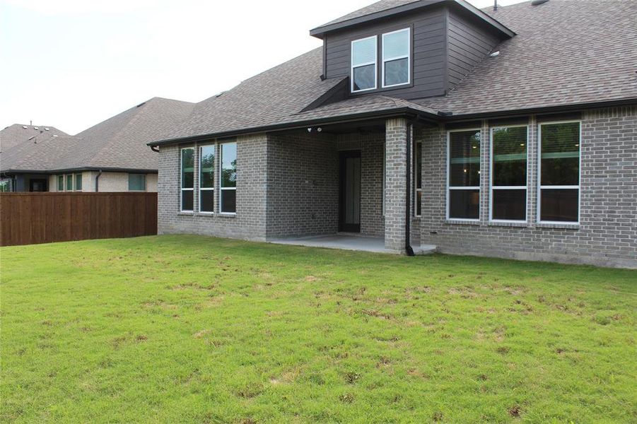 Back of property with brick siding, a patio area, and roof with shingles