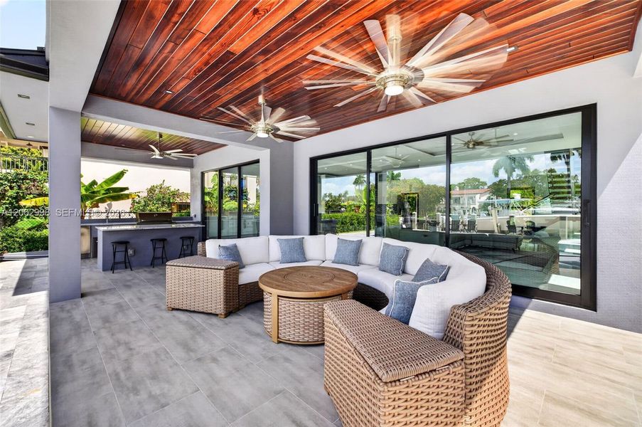 Covered patio w/ T&G ceilings, fans, fire pit seating and outdoor kitchen overlooks the gorgeous wide New River views and pool area
