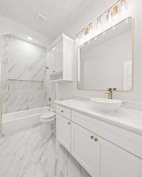 Bathroom featuring a white vanity with gold hardware, a vessel sink, and a framed mirror Bathroom featuring a white vanity with gold hardware, a vessel sink, and a framed mirror