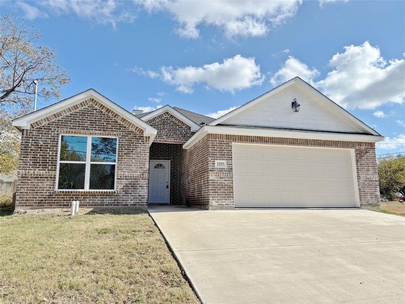 Ranch-style house with driveway, a front lawn, brick siding, and an attached garage