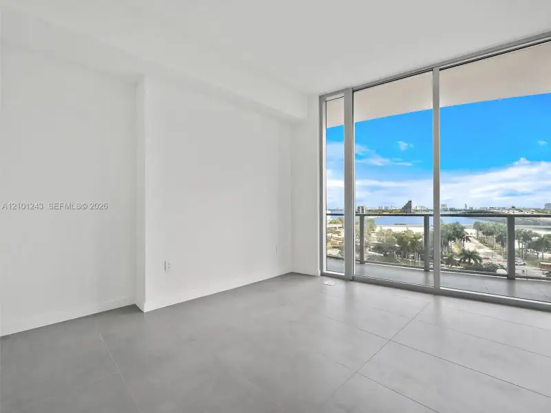 Floor-to-ceiling glass windows, ceramic tile flooring, and a covered balcony featuring a glass panel railing Floor-to-ceiling glass windows, ceramic tile flooring, and a covered balcony featuring a glass panel railing