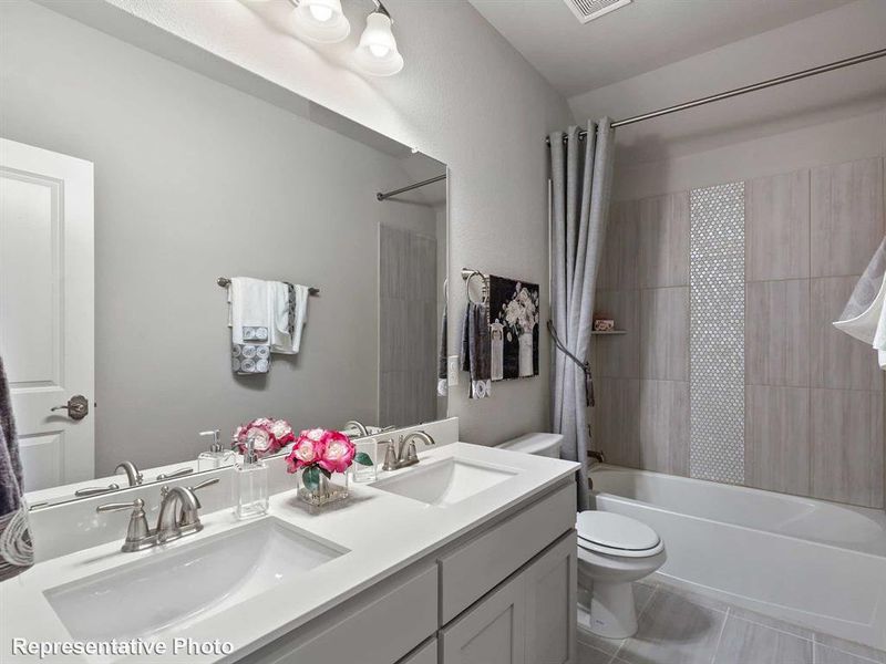 Full bathroom with tile patterned flooring, dual vanity, toilet, and shower / tub combo with curtain