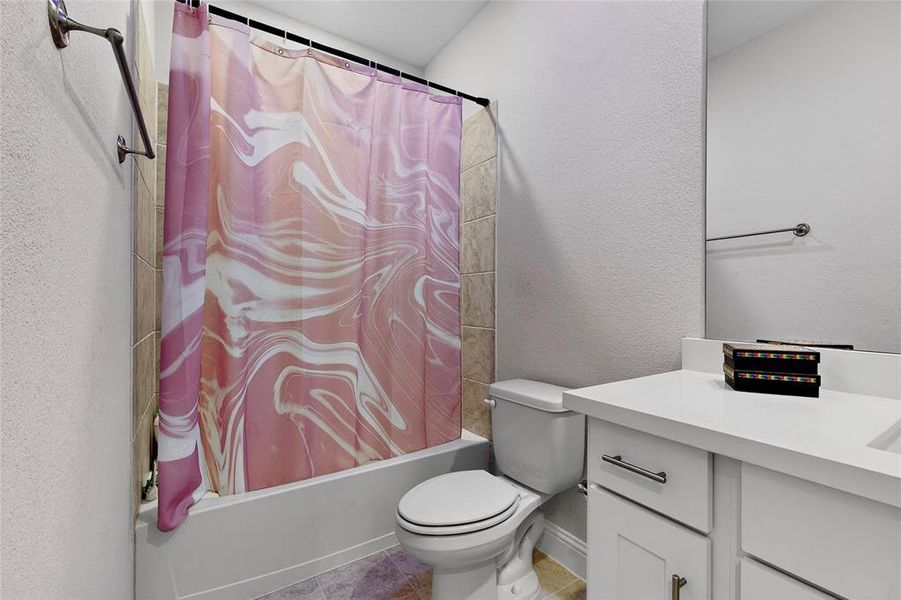 Bathroom featuring a textured wall, vanity, shower / bath combo, and light tile patterned flooring