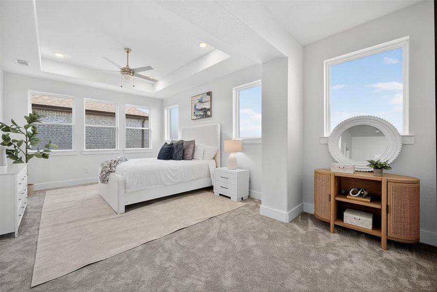 Bedroom with light colored carpet, multiple windows, a ceiling fan, a raised ceiling, and recessed lighting Bedroom with light colored carpet, multiple windows, a ceiling fan, a raised ceiling, and recessed lighting