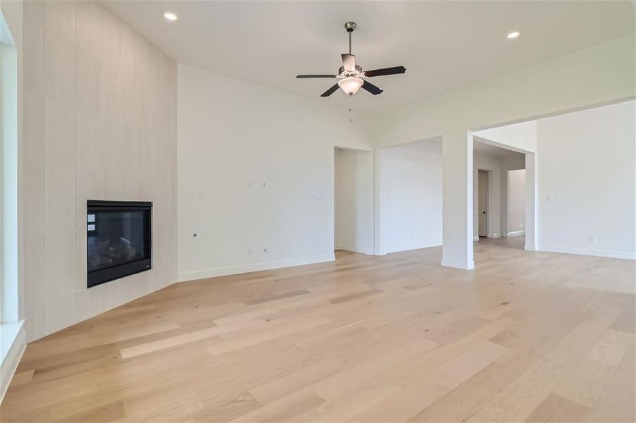 Unfurnished living room featuring ceiling fan, light hardwood / wood-style flooring, and a large fireplace