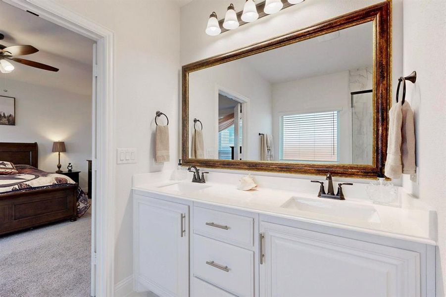 Ensuite bathroom with double vanity, a shower with shower door, and ceiling fan