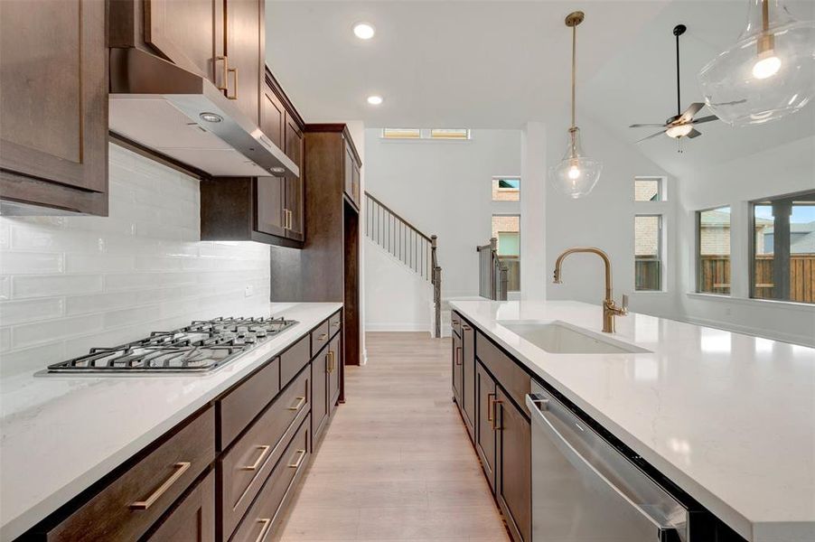 Gourmet kitchen with dark wood cabinetry, white quartz countertops, subway tile backsplash, and stainless steel appliances