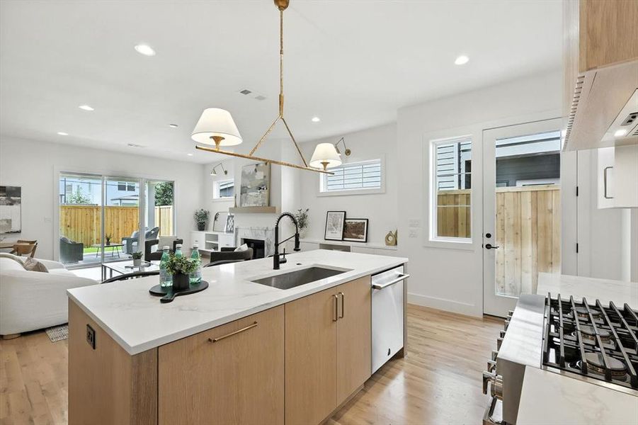 Kitchen featuring open floor plan, light stone counters, light brown cabinets, light wood-type flooring, and modern cabinets Kitchen featuring open floor plan, light stone counters, light brown cabinets, light wood-type flooring, and modern cabinets