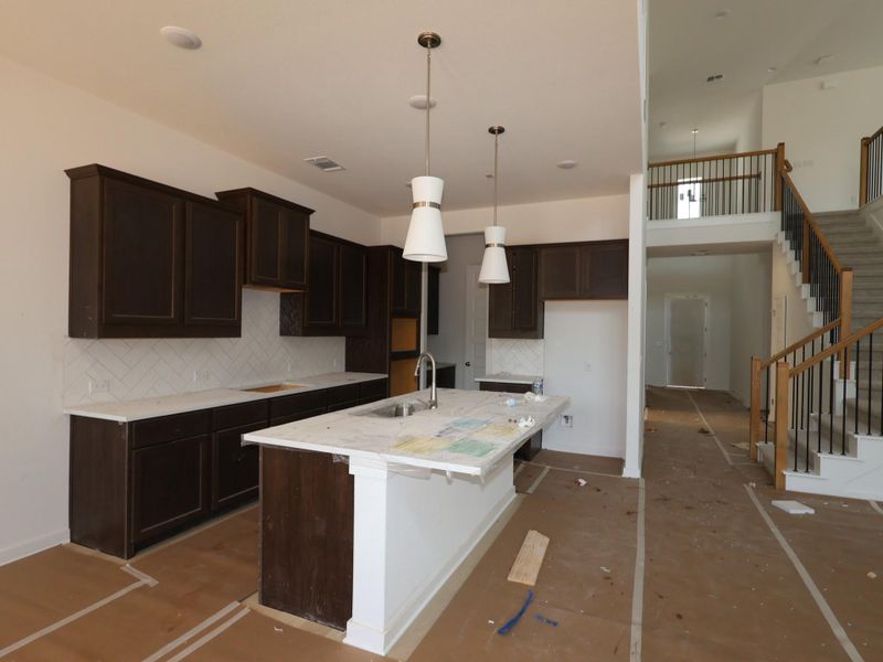 A well-lit kitchen with dark cabinetry and an inviting island seamlessly flows into an open living space.