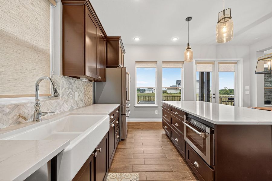 Bright kitchen with farmhouse sink, herringbone backsplash, and picturesque lake views from oversized windows. Bright kitchen with farmhouse sink, herringbone backsplash, and picturesque lake views from oversized windows.
