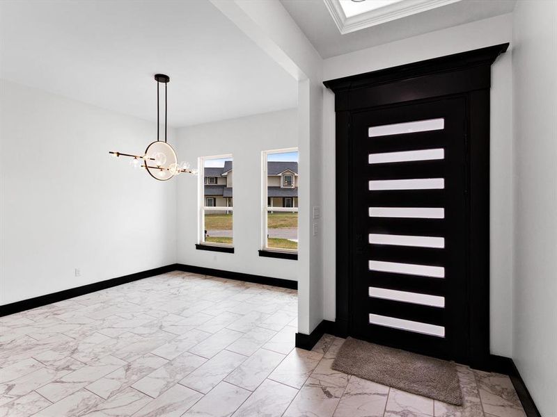 Entryway featuring a modern black door with horizontal glass inserts, a contemporary chandelier, two rectangular windows, and large format marble-look tile flooring