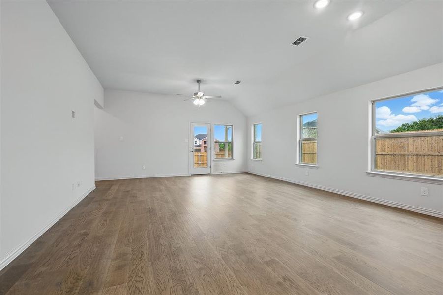Unfurnished living room with wood finished floors, lofted ceiling, and a ceiling fan Unfurnished living room with wood finished floors, lofted ceiling, and a ceiling fan
