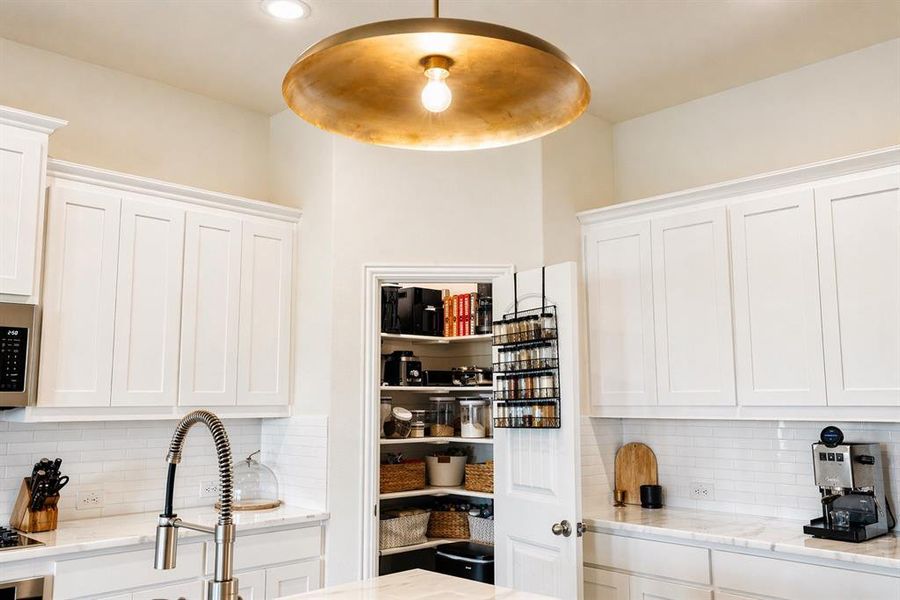 Kitchen featuring white shaker-style cabinetry, a subway tile backsplash, and stone countertops