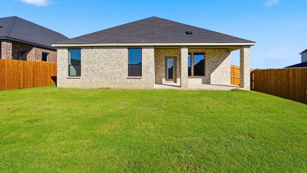 Back of house with brick siding, a fenced backyard, a patio, and a shingled roof