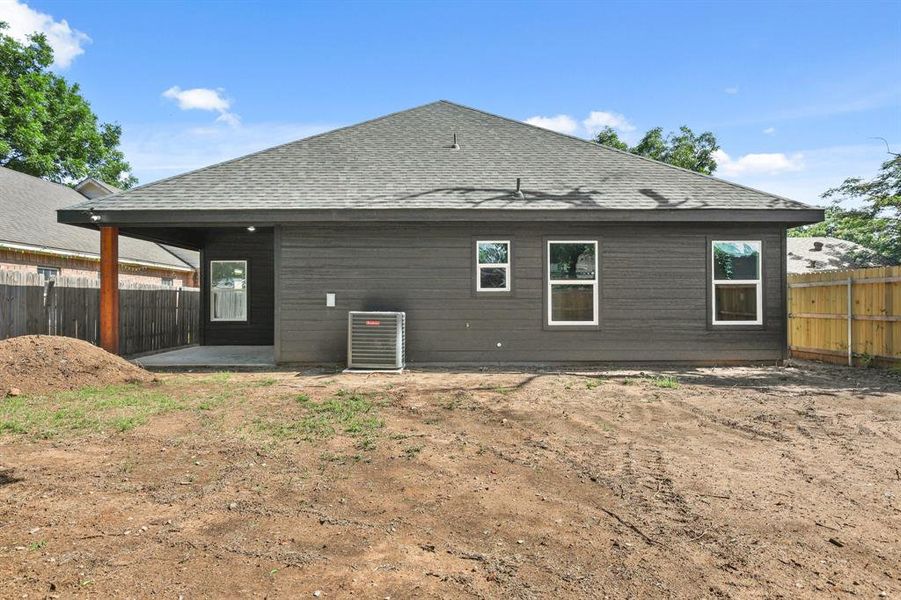 Back of house featuring cooling unit, roof with shingles, and a patio area