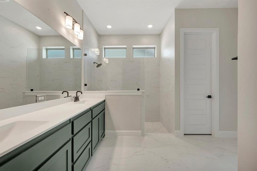 Spacious bathroom featuring a dual vanity with dark green cabinetry and a light-toned countertop, a large walk-in shower with tile walls and a rain showerhead, expansive mirror, and recessed lighting
