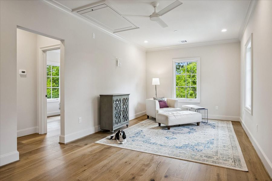 Another view of the spacious living area in the mother-in-law/guest suite with gleaming hardwood flooring, crown molding, modern ceiling fan and recessed lighting, providing a versatile setting for lounging or extended stays. The open layout allows for comfortable seating and flexible use with the bedroom to the suite attached!