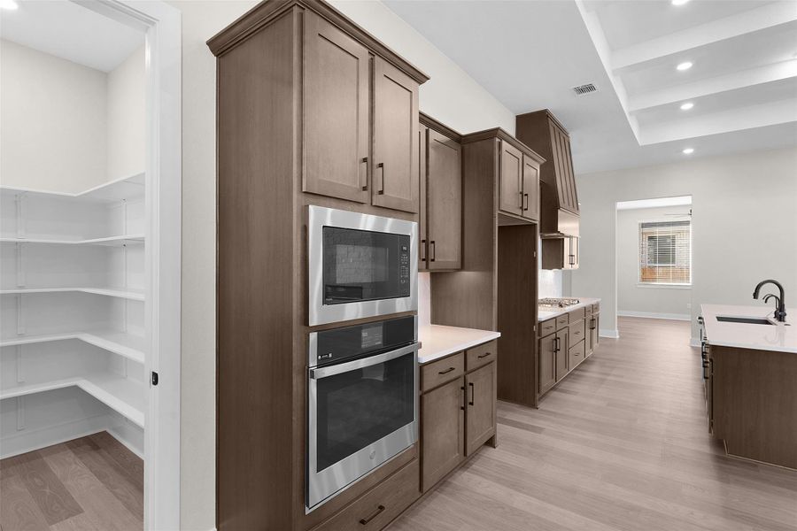 Kitchen with recessed lighting, oven, built in microwave, light wood-type flooring, and light stone counters