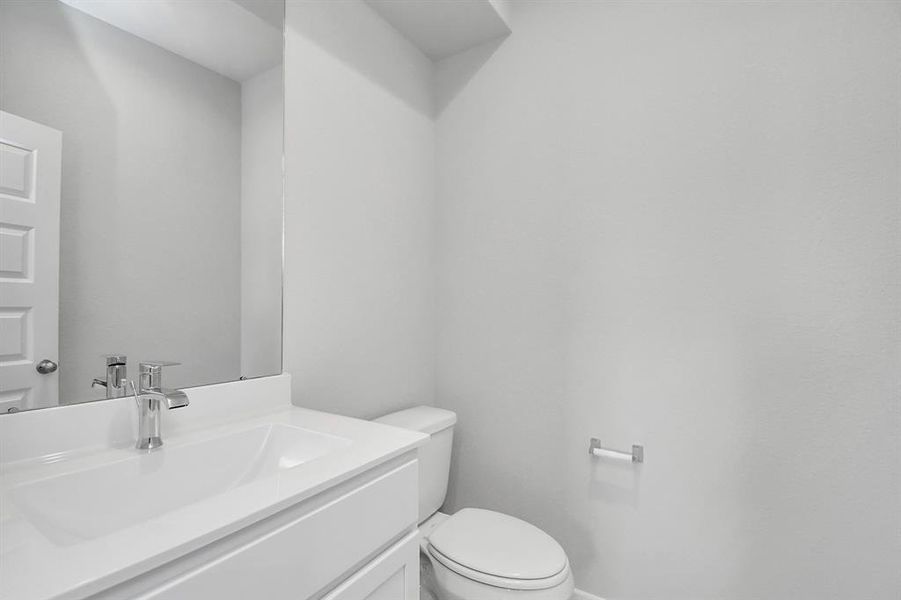 This half bathroom features a stylish pedestal sink, modern hardware, and bright recessed lighting, creating a sleek and inviting space.  Sample photo of completed home with similar plan. As built color and selections may vary.