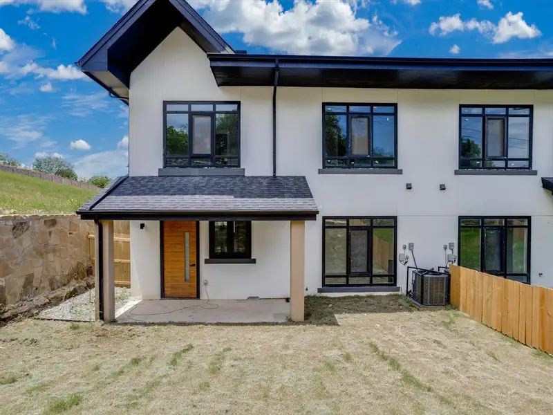 Modern exterior featuring a prominent black gable roofline, white stucco siding, and black-framed windows Modern exterior featuring a prominent black gable roofline, white stucco siding, and black-framed windows