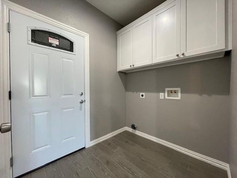 Laundry room with hookup for a washing machine, ceramic wood-style flooring, baseboards, cabinet space, and electric dryer hookup Laundry room with hookup for a washing machine, ceramic wood-style flooring, baseboards, cabinet space, and electric dryer hookup