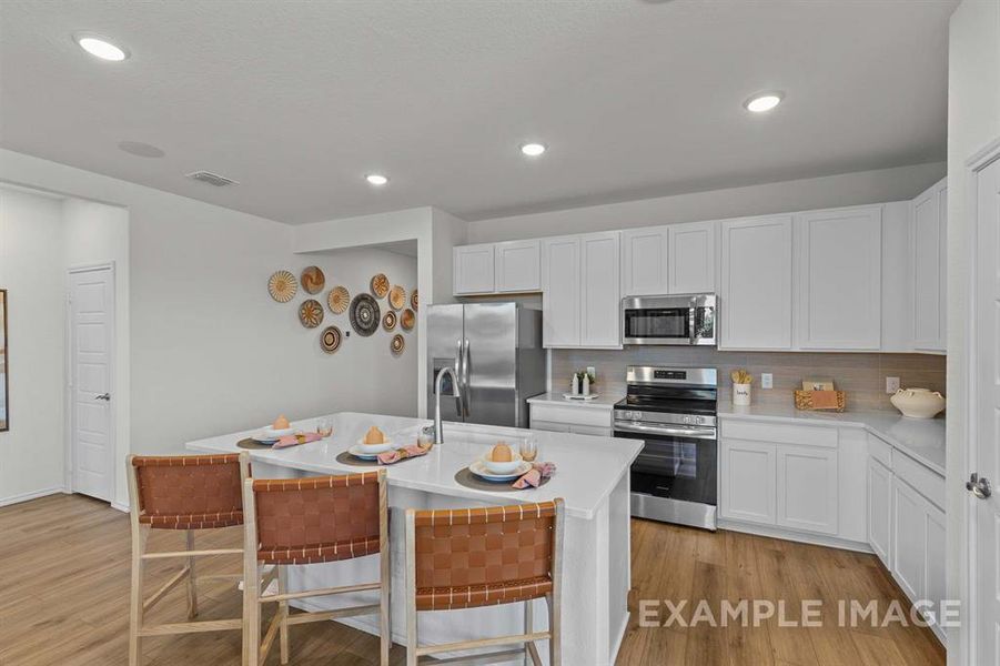 Kitchen featuring a breakfast bar area, white cabinetry, a center island with sink, and stainless steel appliances