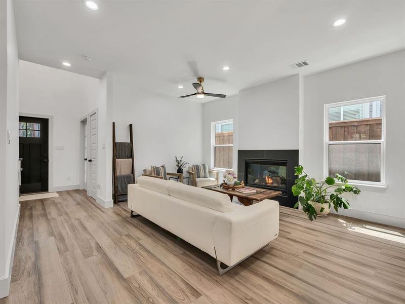 Living room with recessed lighting, light wood-type flooring, a multi sided fireplace, plenty of natural light, and ceiling fan Living room with recessed lighting, light wood-type flooring, a multi sided fireplace, plenty of natural light, and ceiling fan