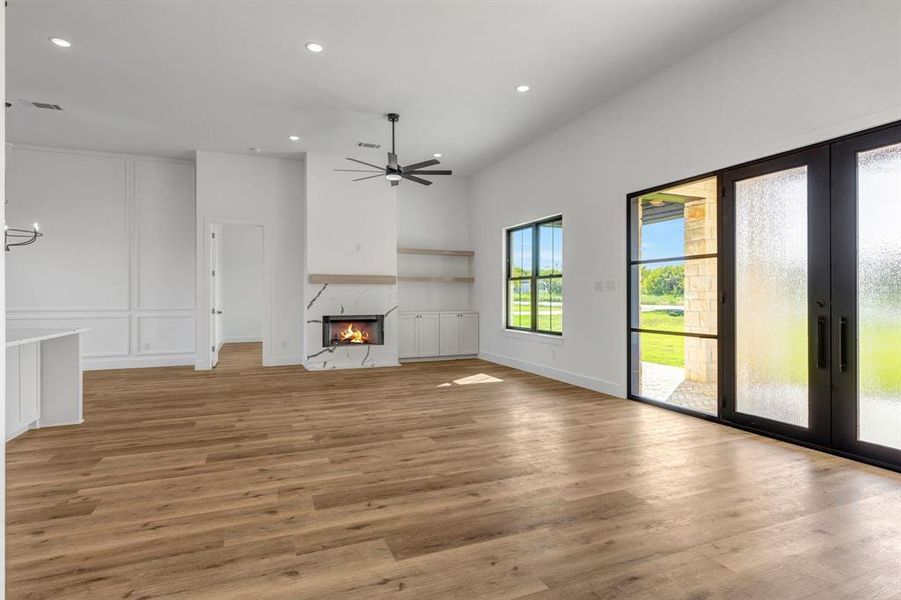 Living room with recessed lighting, light wood-type flooring, a premium fireplace, Iron doors, and a ceiling fan