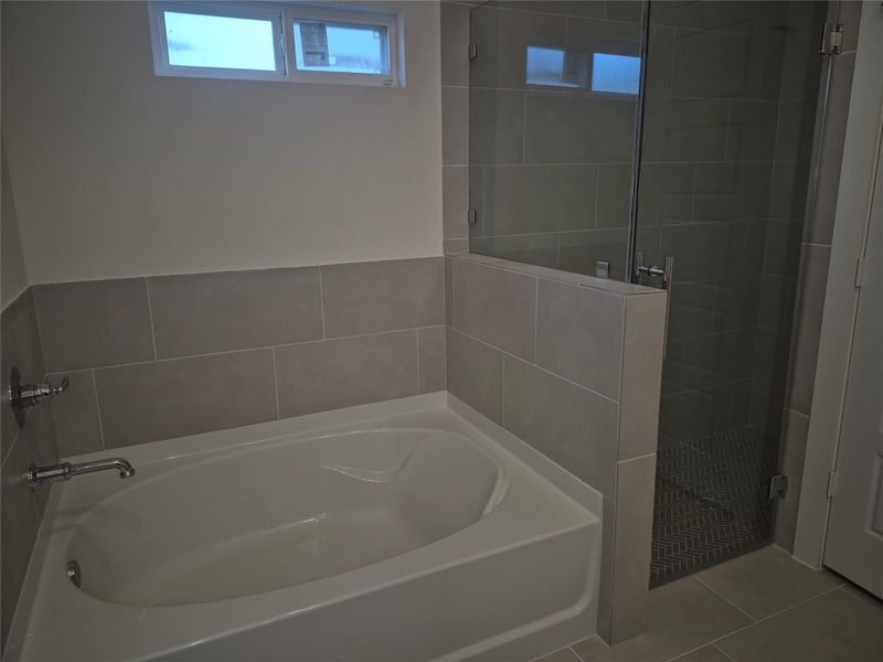 Modern bathroom featuring a spacious bathtub and a sleek glass-enclosed shower, accented with contemporary tile work.