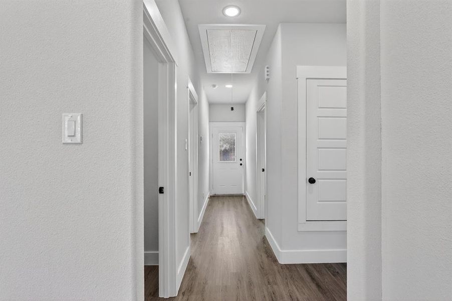 Hallway featuring wood-finish flooring, recessed lighting, and crisp white trim
