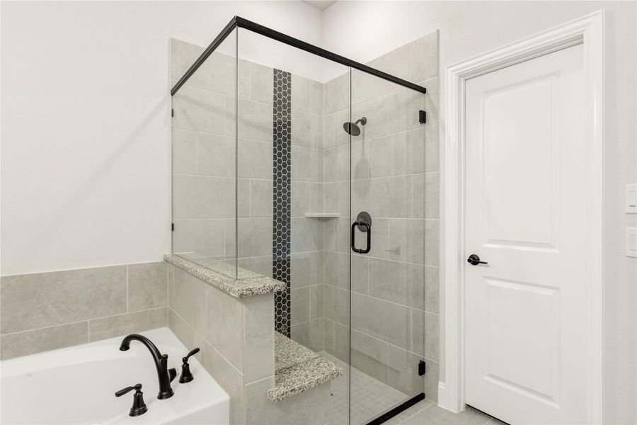 Bathroom with glass-enclosed tile shower, built-in bench, and soaking tub with black fixtures