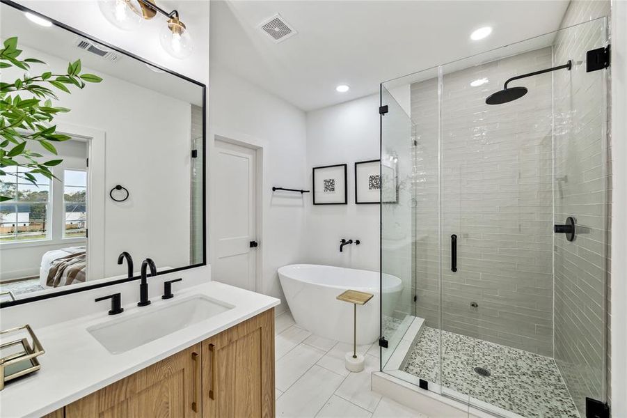 Experience luxury in the primary bathroom, featuring a sleek glass shower, elegant freestanding tub, and modern fixtures.