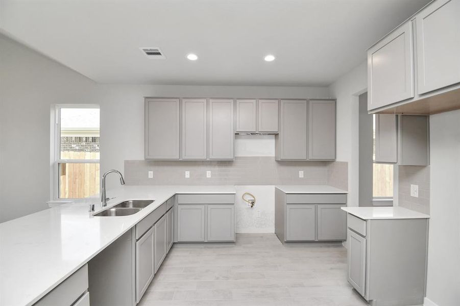 Culinary haven, featuring quartz countertops, a tile backsplash, stainless steel appliances, and 42” upper cabinets. Sample photo of completed home with similar floor plan. Actual colors and selections may vary.