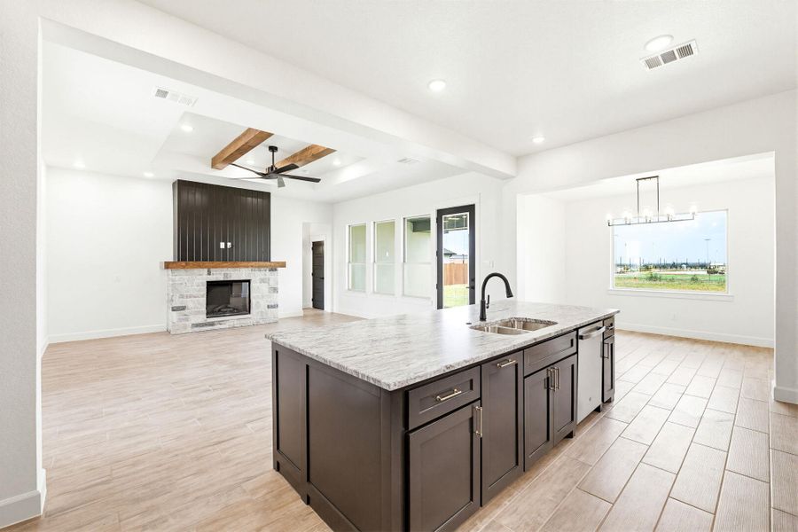 A spacious, naturally illuminated interior with a central kitchen island and a charming fireplace. A spacious, naturally illuminated interior with a central kitchen island and a charming fireplace.