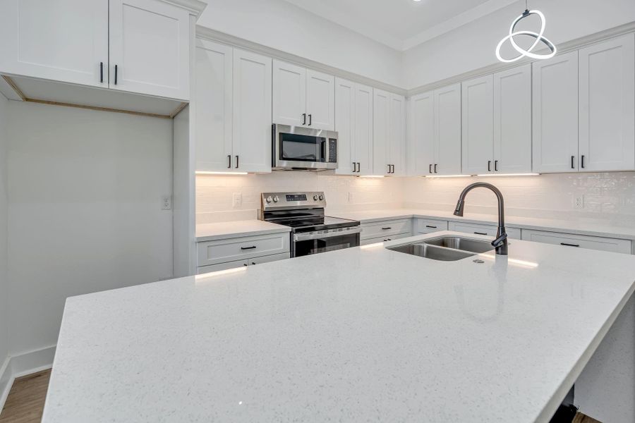Oversized waterfall quartz island with built-in sink overlooking the living area, creating an open layout ideal for entertaining.
