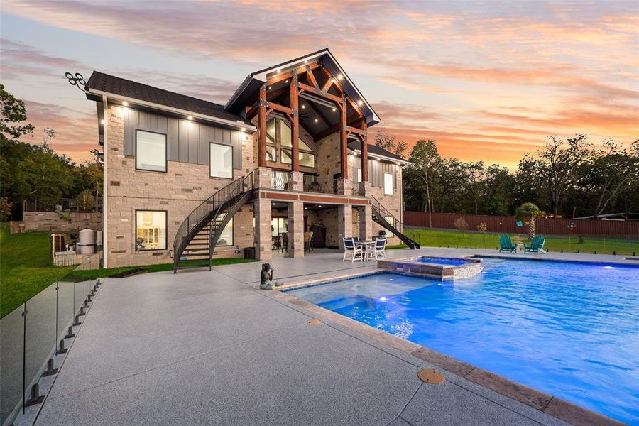 Pool at dusk with stairway, a patio, and a pool with connected hot tub Pool at dusk with stairway, a patio, and a pool with connected hot tub