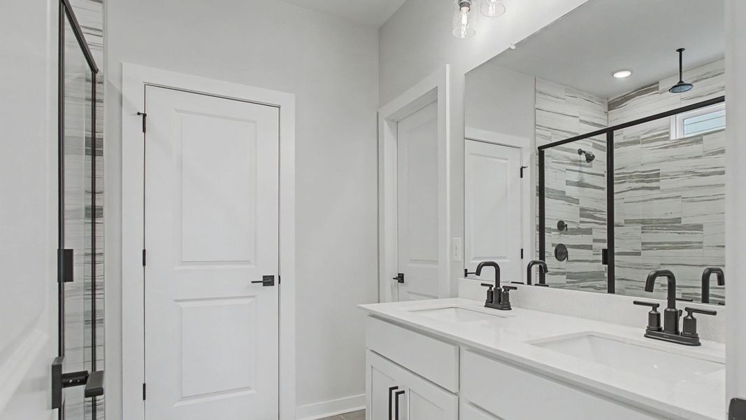 Bathroom with dual sink vanity, quartz countertop, and tiled floors and shower