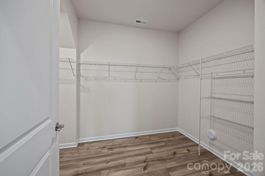 PRIMARY CLOSET -- Oh my goodness! Enjoy this one!! Notice the continuous LVP flooring throughout the first floor bedrooms and closet.  Wonderful!