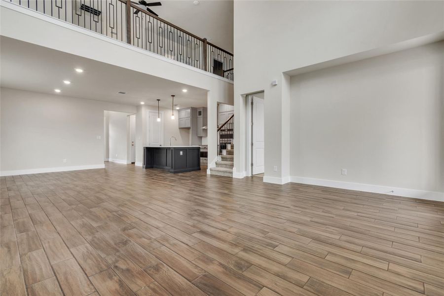 A spacious and modern interior features high ceilings, a loft overlooking the living area, and durable wood-look tile flooring.